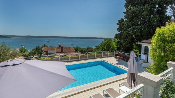 En swimmingpool med utsikt över havet och båtarna.