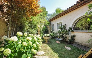 Ein Garten mit einem weißen Gebäude, Steinstufen und verschiedenen Pflanzen.