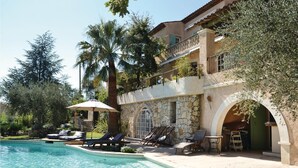 Ein Poolbereich mit Liegestühlen und ein Steinhaus mit Balkon.