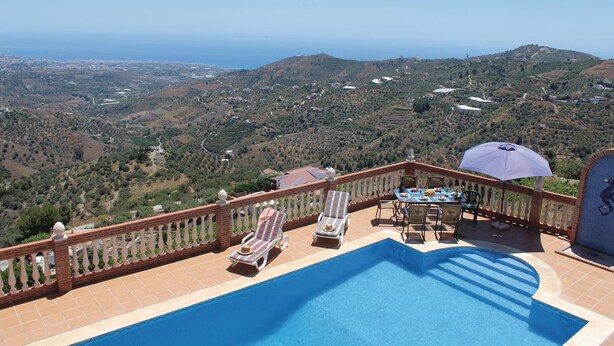 A pool area with a view of the sea and hills.
