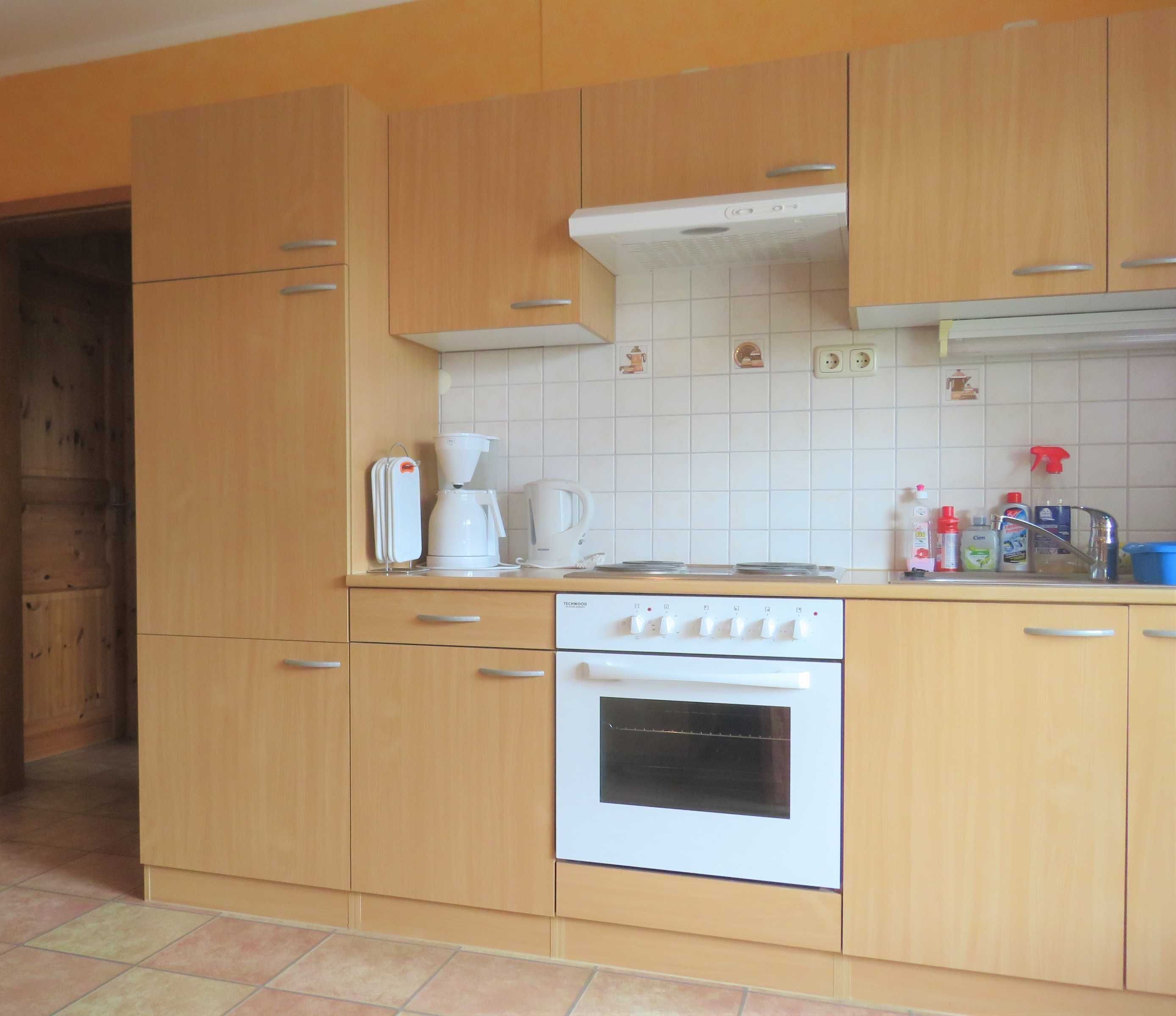 Una cocina con armarios de madera, una estufa blanca y una cafetera.