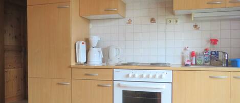 Una cocina con armarios de madera, una estufa blanca y una cafetera.
