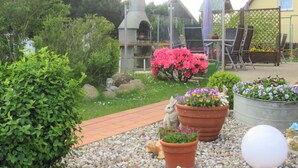 A garden with a stone structure, potted plants, and a statue. - Lod - Kuhtz - Apartment (Loddin)