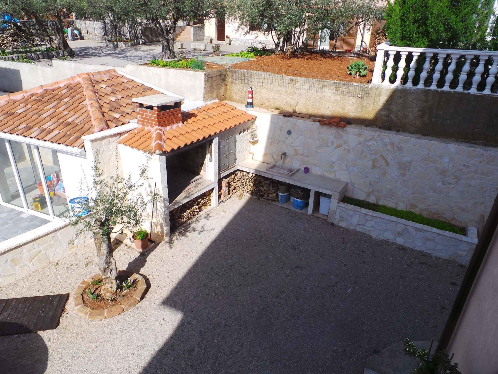 A courtyard with a tiled roof, a small outdoor kitchen, and a stone wall.