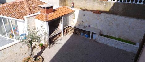 A courtyard with a tiled roof, a small outdoor kitchen, and a stone wall.