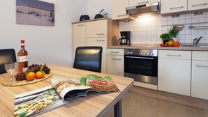 A modern kitchen with a dining area, featuring a coffee maker, a wine bottle, and fresh produce on the counter. - Zempin Ostseepark WE 26 Island Usedom only 150m to the beach - WE 26 (Zempin)