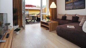 A modern living room with a brown sofa, a wooden coffee table, and a dining area with a table and chairs. - Zempin Ostseepark WE 26 Island Usedom only 150m to the beach - WE 26 (Zempin)