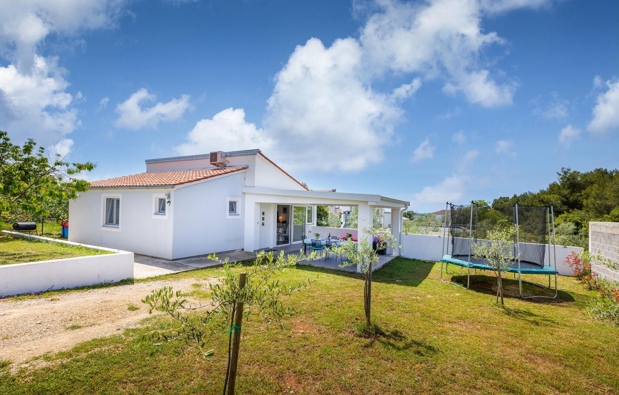 Une maison moderne dotée d’un patio, d’une piscine et d’un jardin.