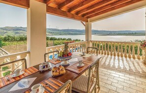 A balcony with a table set for breakfast, overlooking a river and wind turbines. - Beautiful home in Sambuca di Sicilia AG (Sambuca di Sicilia AG)