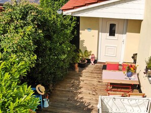 A patio area with a table and chairs, a potted plant, and a small garden.