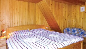 Een houten kamer met een bed, nachtkastje, lamp en een geruite deken.