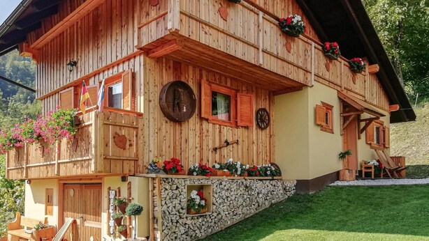 Een klassiek houten chalet met een uitnodigende ingang, een stenen fundering en bloembakken aan de buitenkant.