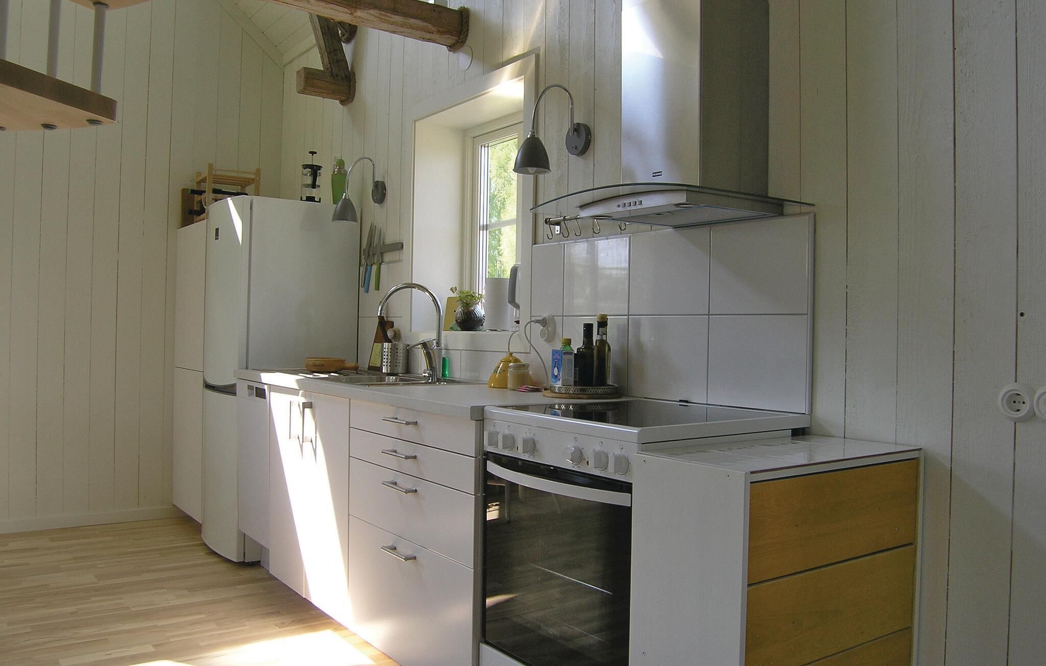 Una cucina compatta con mobili bianchi, forno integrato, lavello e una finestra che offre luce naturale.