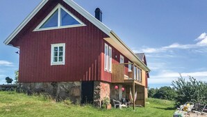 Una casa di legno rossa con un balcone, un camino e un piccolo portico.