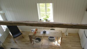 Zona pranzo con tavolo in legno, due sedie e una finestra vista su uccelli e vegetazione.