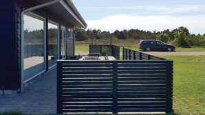 Ein modernes Gebäude mit Glasfassade, einer Holzterrasse und einem geparkten Auto davor.