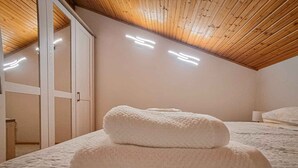 Une chambre avec un plafond en bois, un lit recouvert d’une couvre-lit à motifs floraux et deux serviettes enroulées posées sur le lit.