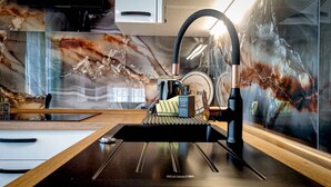 Une cuisine moderne avec un dosseret en marbre, une machine à café et un évier.