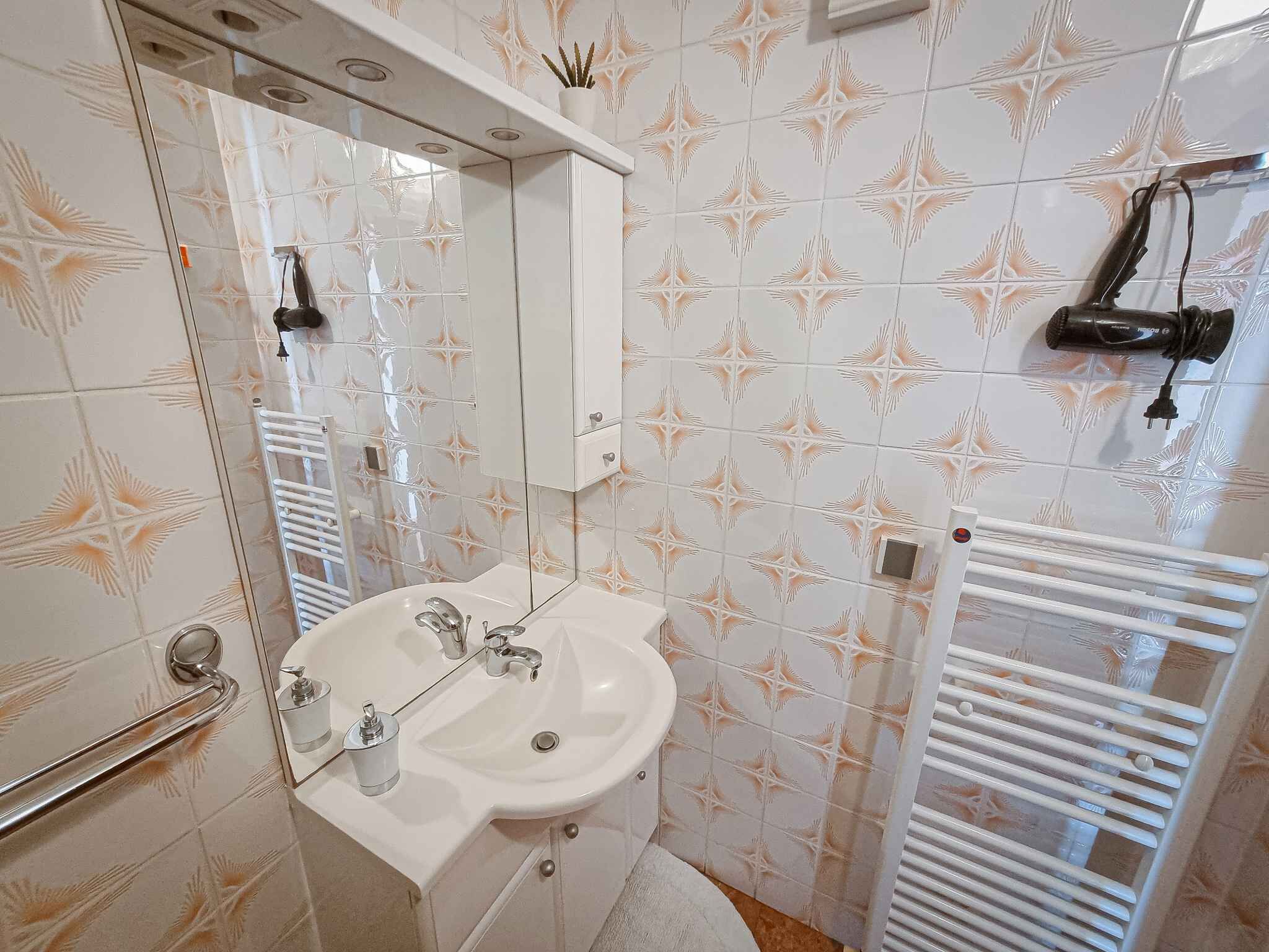 Ein Badezimmer mit weißem Waschbecken, Spiegel und Handtuchhalter.