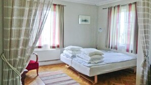 A bedroom with a bed, a chair, and curtains.