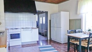 A compact kitchen with a stove, oven, and white cabinets. There's a dining area with a table and chairs, and a window providing natural light.