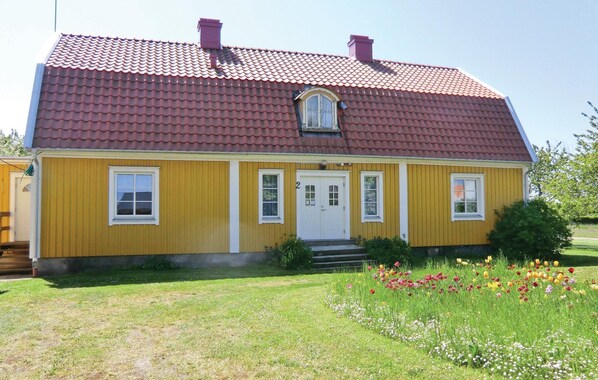 Ein gelbes Haus mit rotem Ziegeldach, einer Haustür und zwei Fenstern.