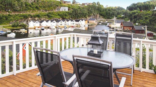 A deck with a table and chairs overlooking a marina with boats and houses.