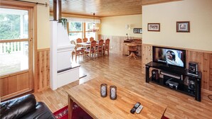 A cozy living room with a wooden floor, a TV, a fireplace, and a dining area with wooden furniture.