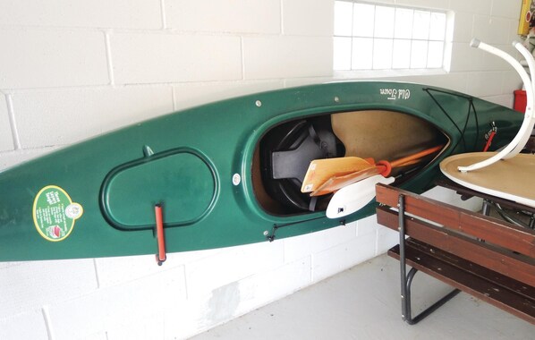 A green kayak with a white interior, mounted on a wall with a window and a bench. - Beautiful home in Ljungby with sauna (Ljungby)