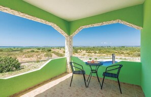 A balcony with two chairs, a table, and a pool.