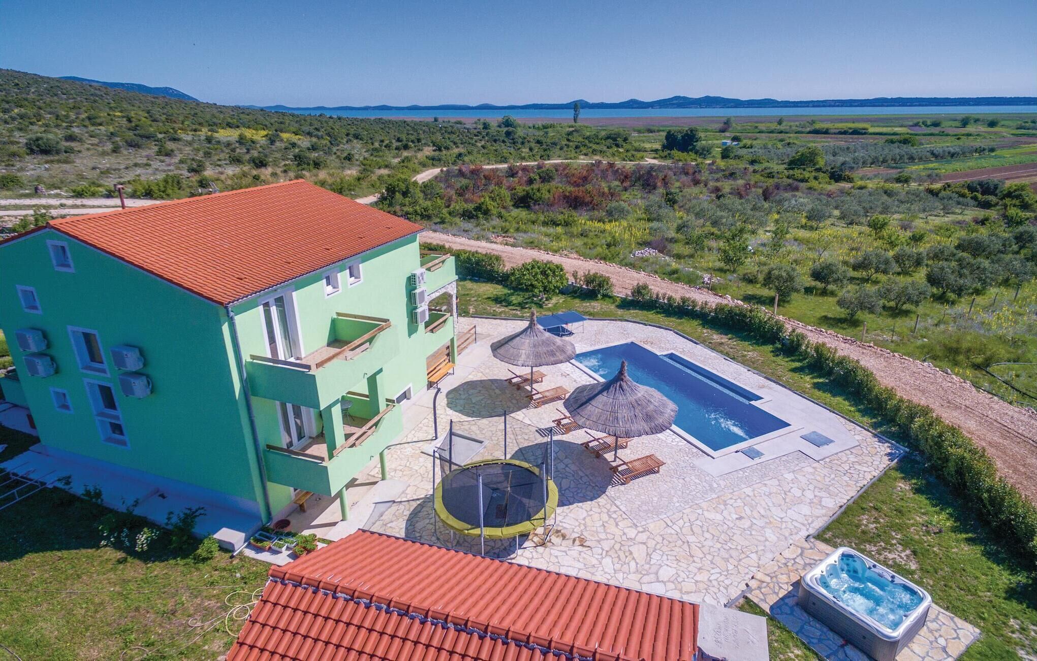 A two-story building with a red roof, a swimming pool, and a hot tub.