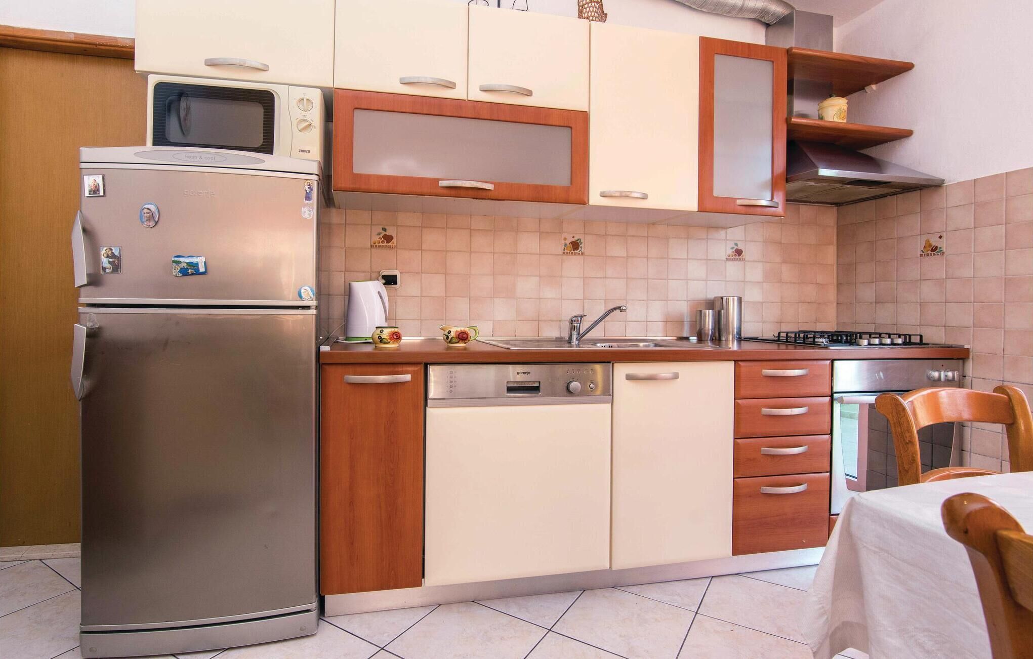 A compact kitchen with a refrigerator, microwave, stove, and dishwasher.