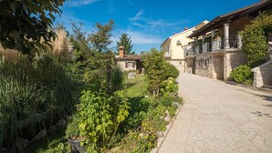 A narrow stone pathway flanked by lush greenery and traditional stone buildings with balconies. - Amazing home in Puzari (Puzari)