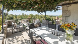 An outdoor patio with stone seating, a table, and a view of the countryside. - Amazing home in Puzari (Puzari)