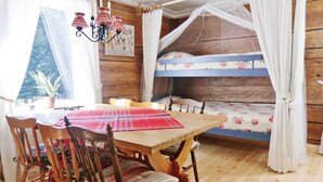 Ein rustikaler Raum mit einem Holzbett, einem Esstisch mit Stühlen und einer Deckenleuchte.