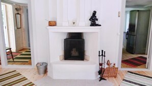 Ein Wohnzimmer mit Kamin, einem Metall-Eimer und einem Korbwannen-Korb.