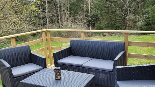 Eine Terrasse mit Korbmöbeln, darunter eine Couch und zwei Stühle, ein kleiner Tisch und eine dekorative Laterne.