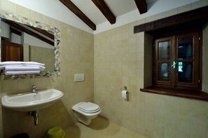 A bathroom with a sink, toilet, and window.