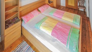 Un letto singolo con una coperta colorata, una testiera in legno e mensole integrate.