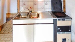 Una cucina con un lavello doppio, un piano cottura integrato e un piccolo frigorifero.