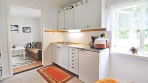 A compact kitchen with white cabinets, a coffee maker, and a window with a view of greenery.