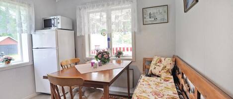 Un comedor acogedor con una mesa de madera, sillas, un banco y un refrigerador.