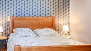 Una cama con cabecera de madera, ropa de cama a rayas y dos lámparas de noche.