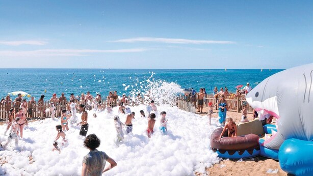 Una playa con estructuras inflables y una multitud de personas.