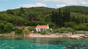 A coastal house with a red roof, surrounded by lush greenery and a clear blue sea. - 1 bedroom pet friendly home in Korcula (Korcula)