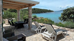 An outdoor patio with a table and chairs, overlooking a body of water and greenery. - 1 bedroom pet friendly home in Korcula (Korcula)
