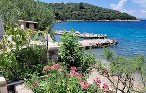 A coastal view with a stone structure, lush greenery, and a clear blue sea. - 1 bedroom pet friendly home in Korcula (Korcula)