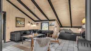 Ein modernes Wohnzimmer mit einer Eckcouch, einem Glastisch und einem Kamin.