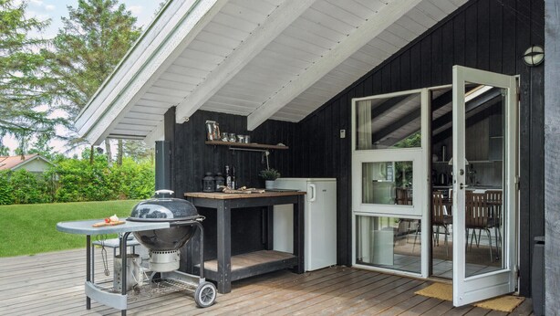 Ein Außenbereich mit Küche, Grill, kleinem Tisch und Kühlschrank.