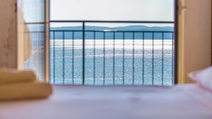A room with a bed and a view of the sea through a window with a metal railing. - 3 bedroom beautiful apartment in Omis (Omis)